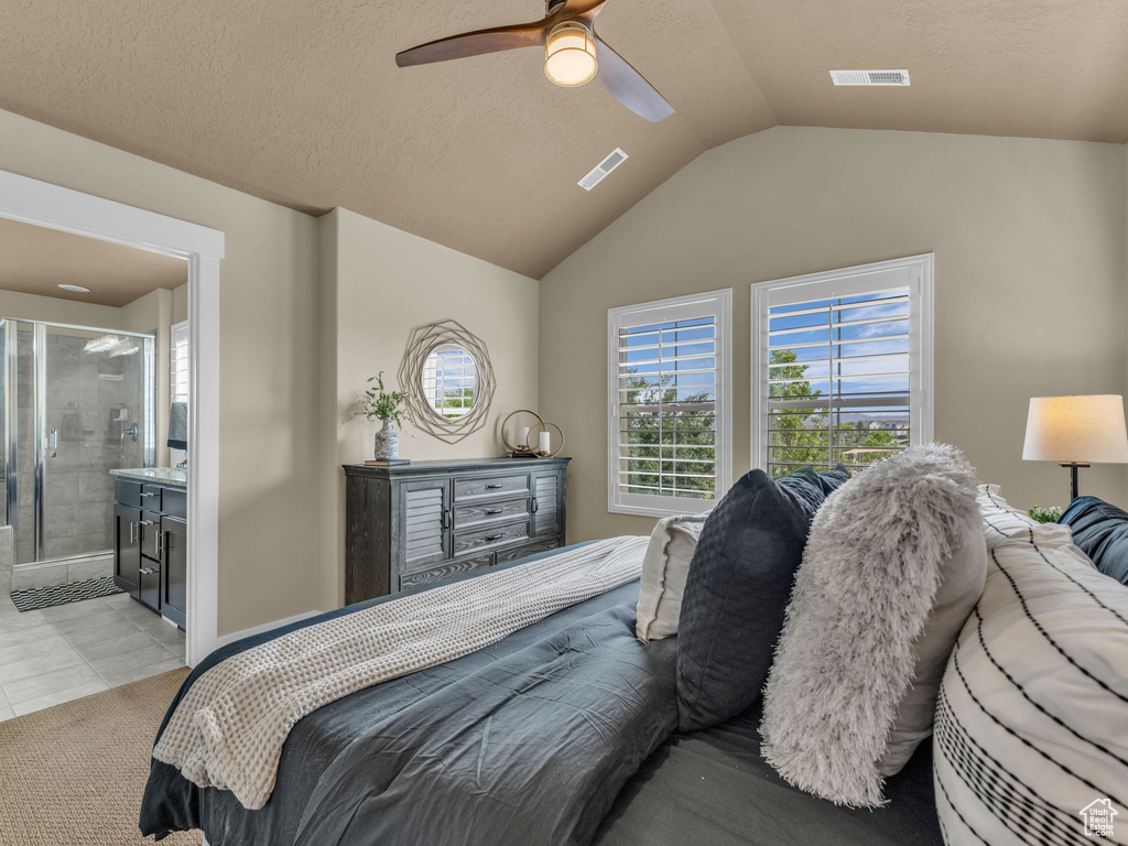 Bedroom featuring lofted ceiling, ensuite bath, ceiling fan, and light tile patterned flooring