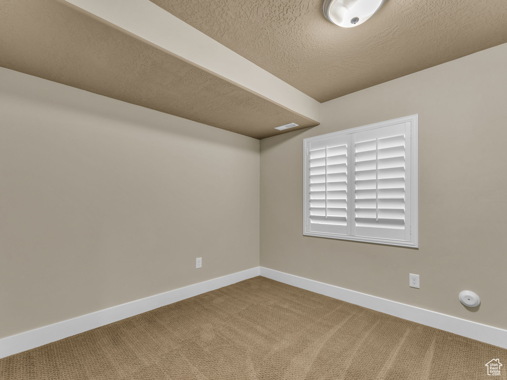 Carpeted empty room with baseboards and a textured ceiling