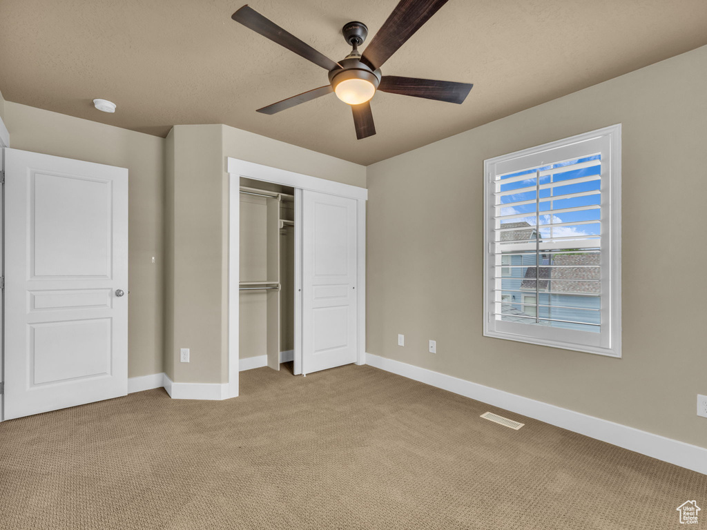 Unfurnished bedroom with carpet flooring, a closet, and a ceiling fan