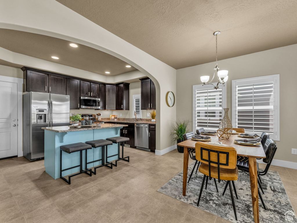 Dining space with arched walkways, a chandelier, a textured ceiling, and recessed lighting