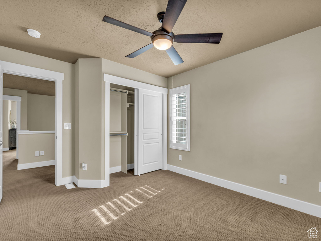 Unfurnished bedroom featuring carpet floors, a textured ceiling, a closet, and a ceiling fan