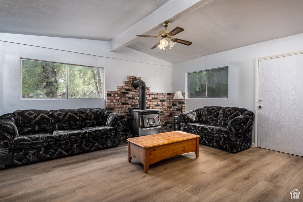 Living area featuring a wood stove, wood finished floors, and a ceiling fan