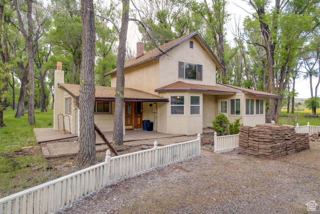 View of front of property with a chimney, stucco siding, and roof with shingles