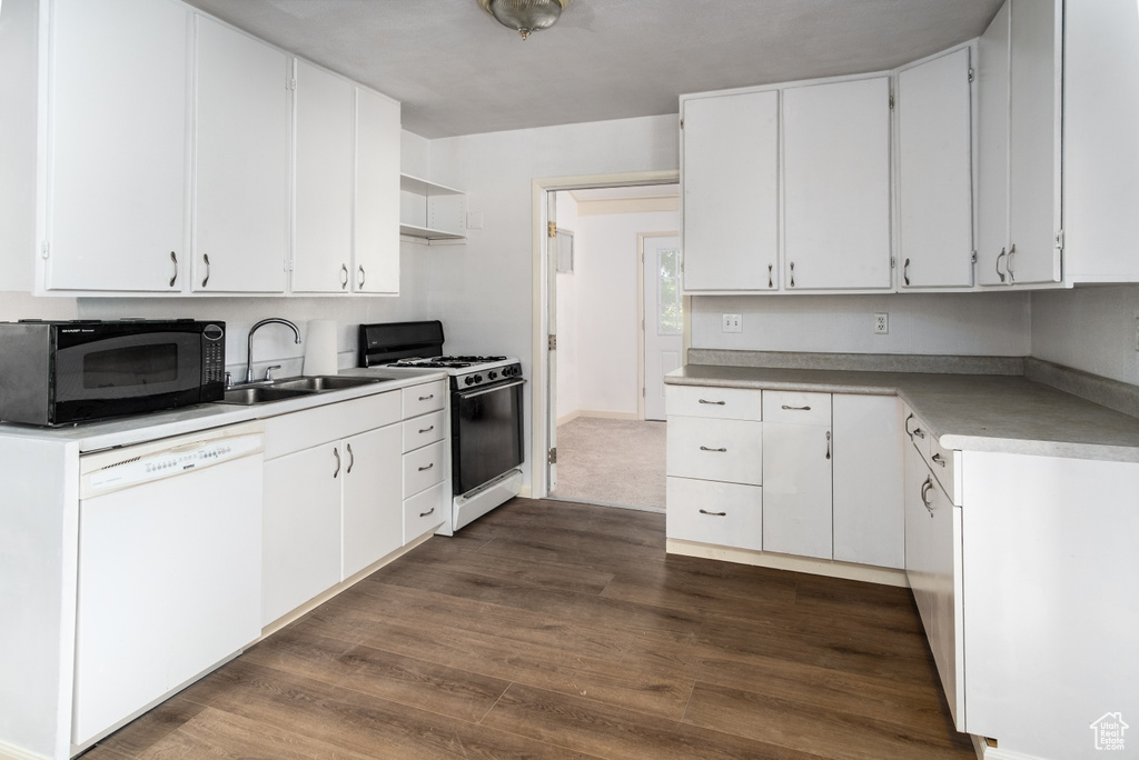 Kitchen with white dishwasher, range with gas cooktop, black microwave, dark wood-type flooring, and white cabinets