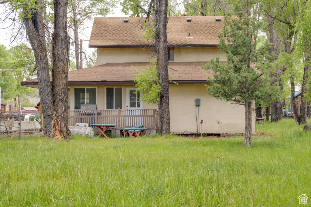 Back of house featuring stucco siding and roof with shingles