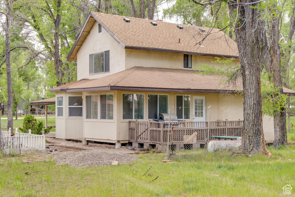 Rear view of house featuring roof with shingles and stucco siding