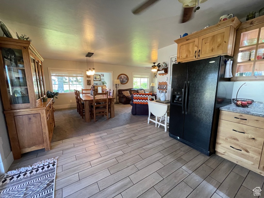 Kitchen with black fridge with ice dispenser, a ceiling fan, light brown cabinets, and wood tiled floors