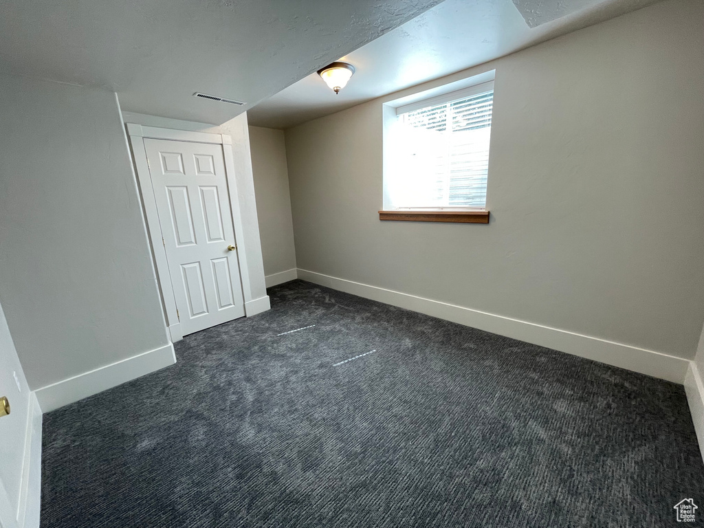 Empty room featuring dark colored carpet and baseboards