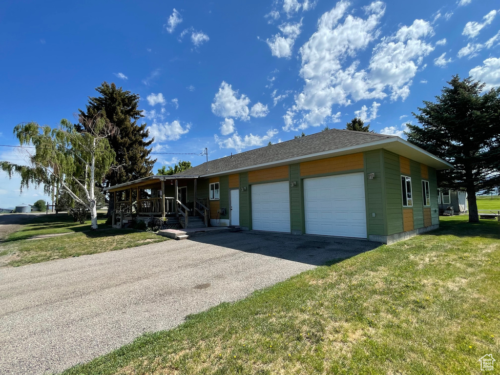 View of front of house featuring an attached garage, driveway, a front lawn, and a porch