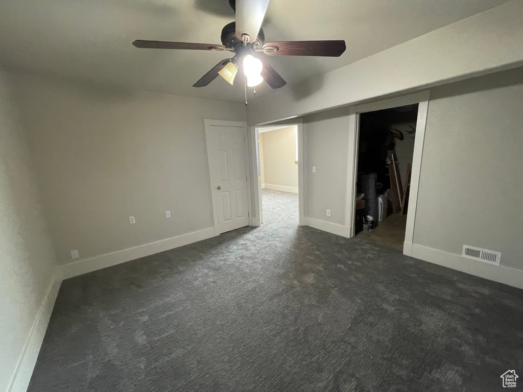 Unfurnished room featuring a ceiling fan and dark colored carpet