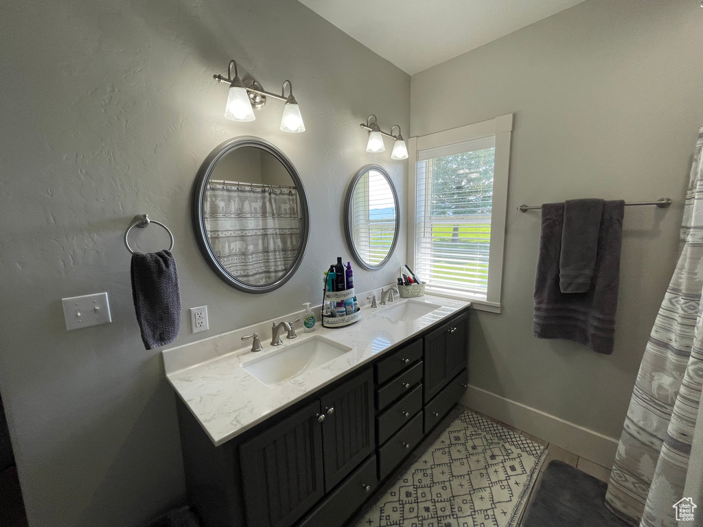 Full bathroom with double vanity and baseboards