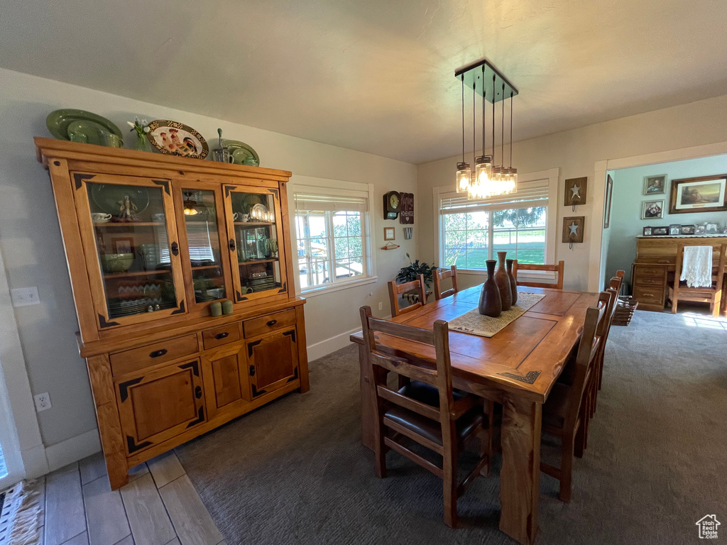 Carpeted dining area featuring a chandelier and baseboards
