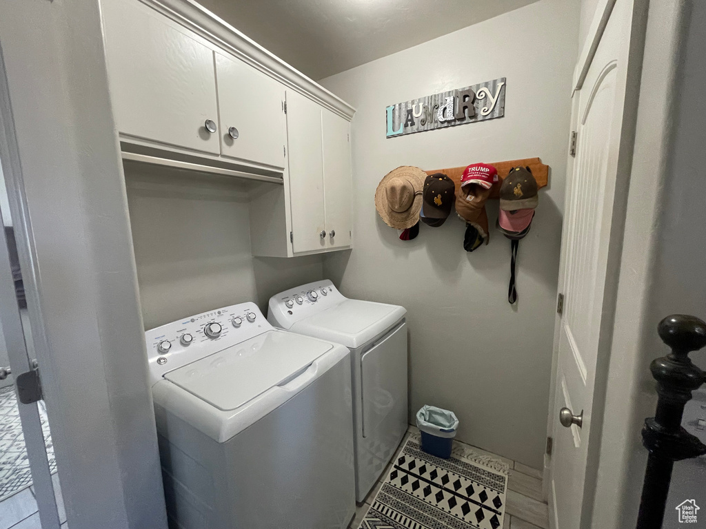 Laundry room featuring washer and clothes dryer, cabinet space, and tile patterned floors