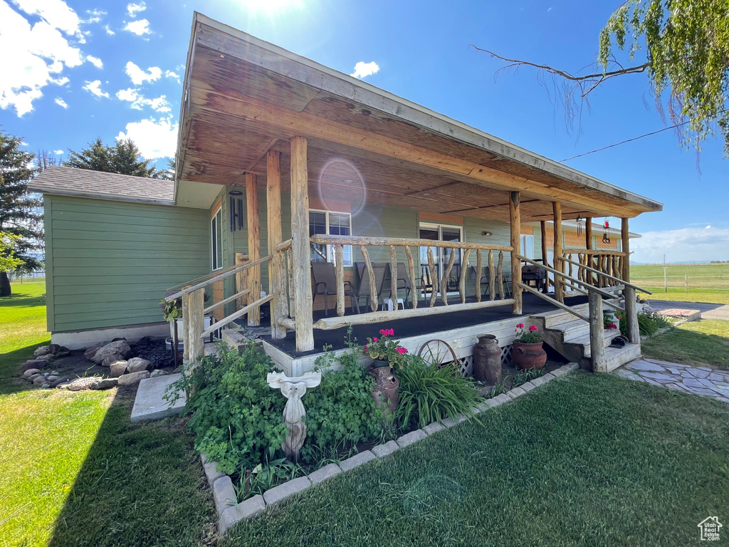 View of side of home featuring covered porch and a yard
