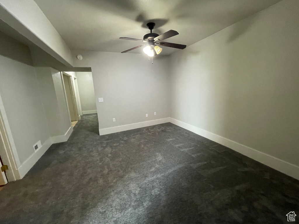 Unfurnished bedroom featuring dark carpet and ceiling fan