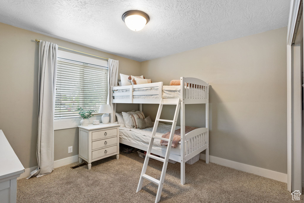 Carpeted bedroom with a textured ceiling and baseboards