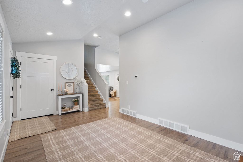 Foyer with stairway, recessed lighting, wood finished floors, and vaulted ceiling