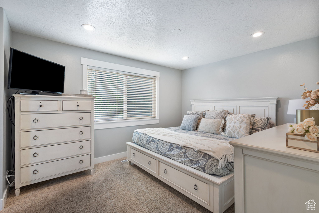Bedroom with light colored carpet, recessed lighting, and a textured ceiling