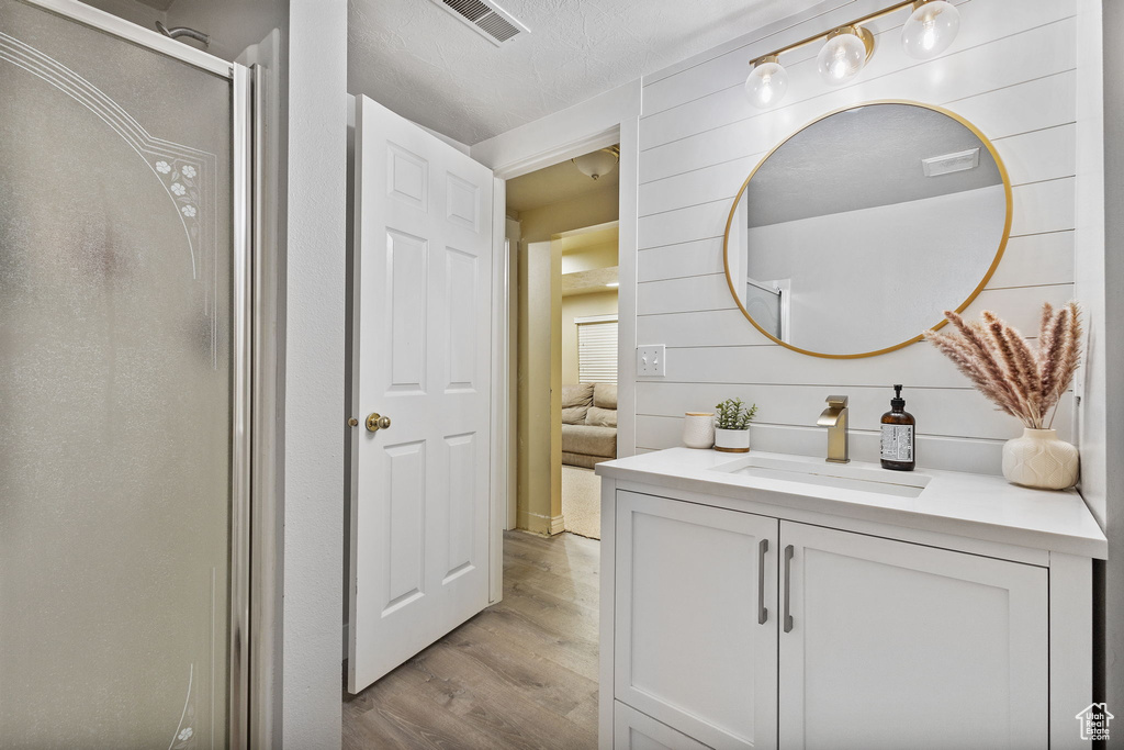 Ensuite bathroom with wood finished floors, vanity, and a stall shower