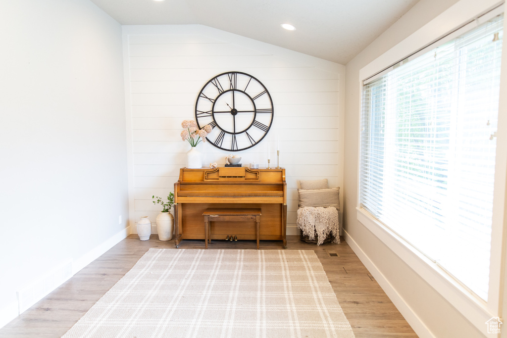 Sitting room with plenty of natural light, wood finished floors, lofted ceiling, and recessed lighting