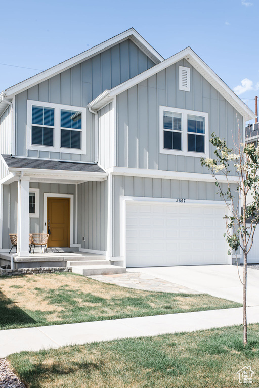 View of front of property featuring board and batten siding, an attached garage, covered porch, and driveway