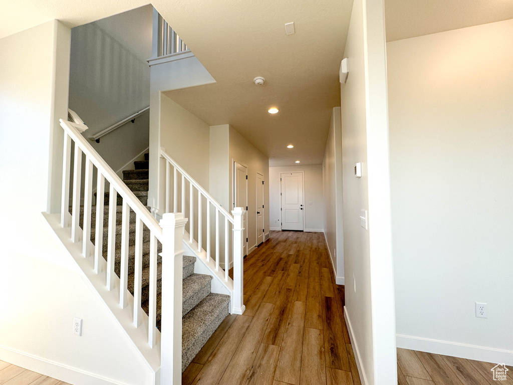 Staircase featuring wood finished floors and recessed lighting