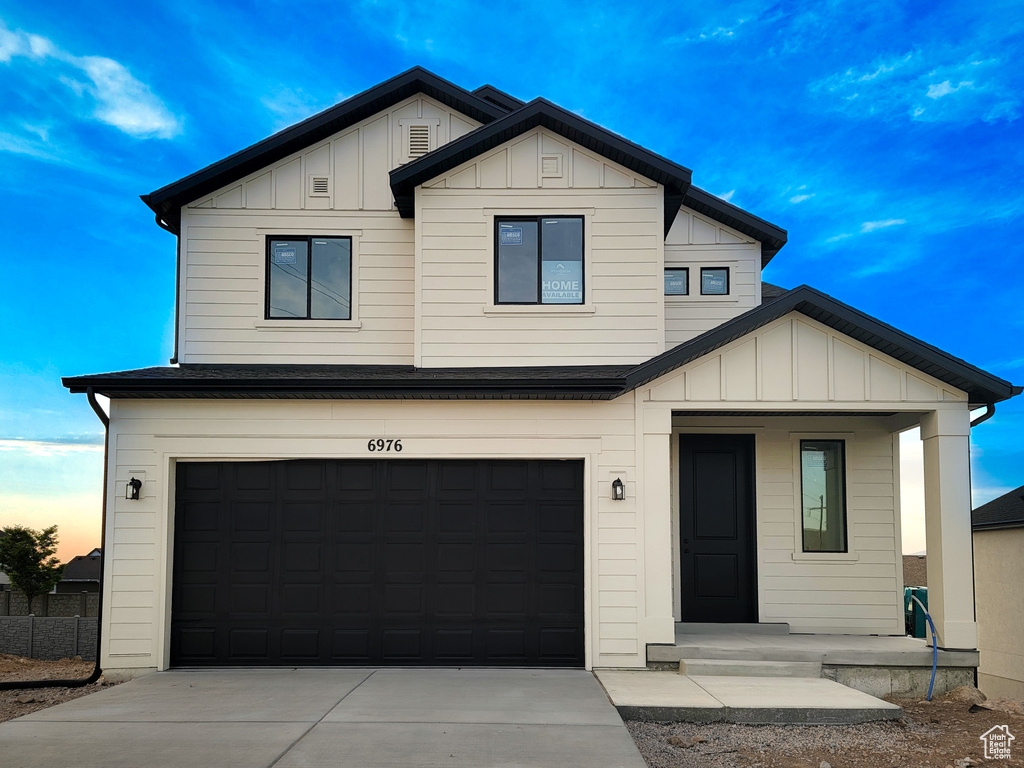 View of front facade with board and batten siding, an attached garage, and driveway