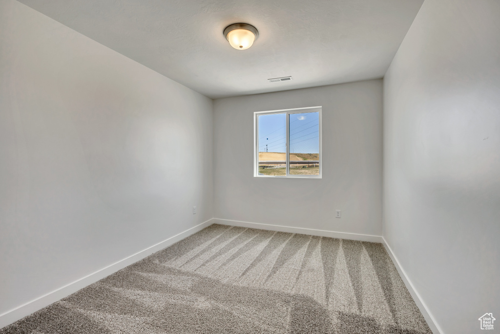 Carpeted spare room featuring baseboards
