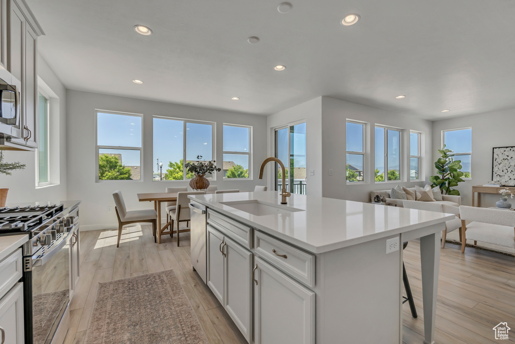 Kitchen featuring appliances with stainless steel finishes, recessed lighting, light countertops, a breakfast bar area, and open floor plan