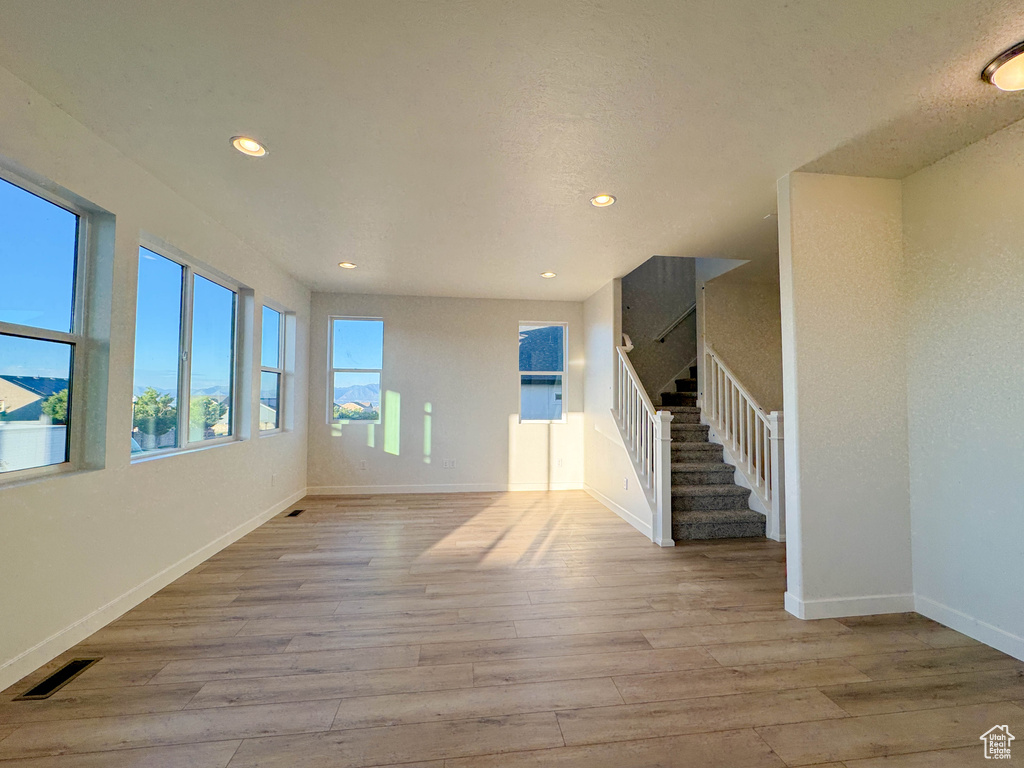 Unfurnished living room featuring wood finished floors, stairway, and recessed lighting