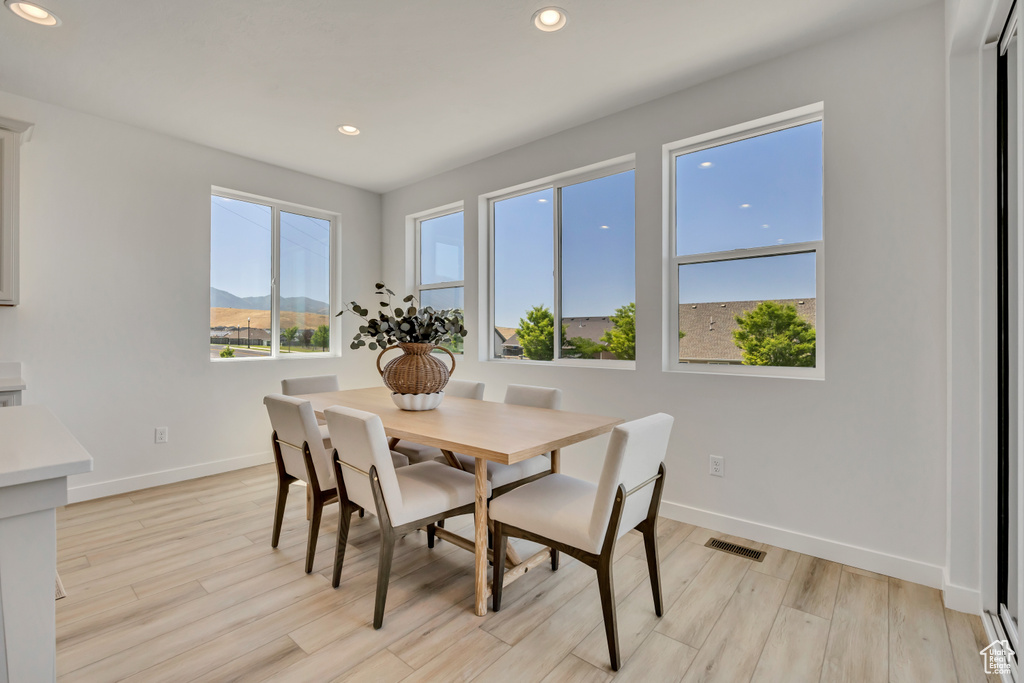 Dining room with light wood finished floors and recessed lighting