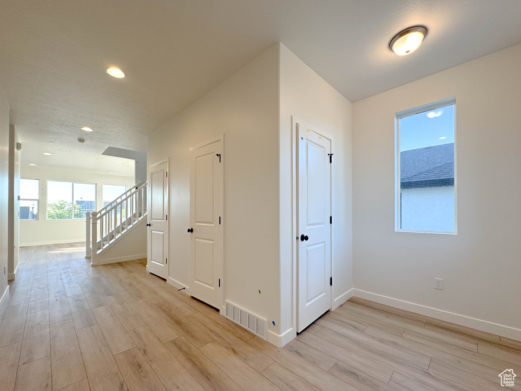 Hallway featuring light wood-style flooring, stairway, and recessed lighting