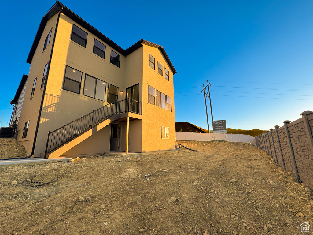 Rear view of property featuring stairs and stucco siding