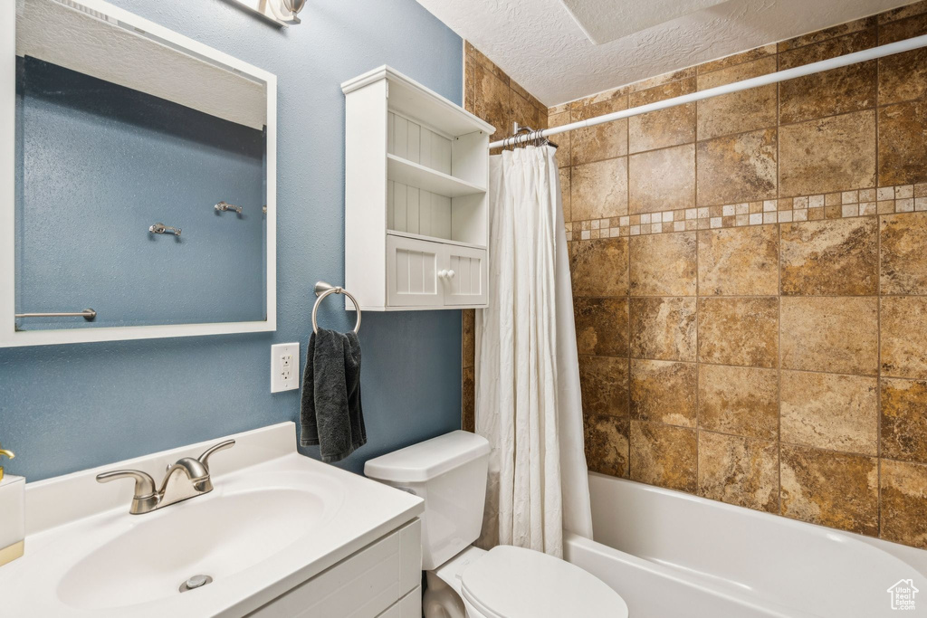 Bathroom featuring vanity, shower / bath combo with shower curtain, and a textured ceiling