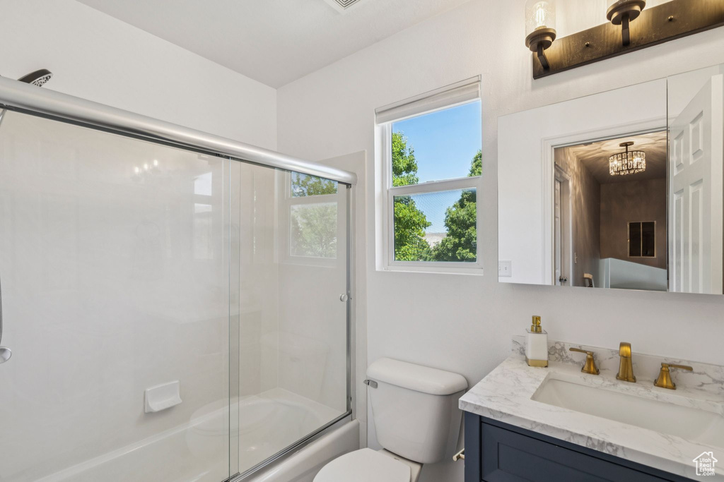 Full bath featuring vanity, shower / bath combination with glass door, and a chandelier