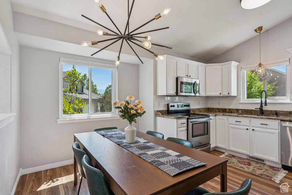 Kitchen featuring stainless steel appliances, dark wood-style flooring, a chandelier, tasteful backsplash, and white cabinets