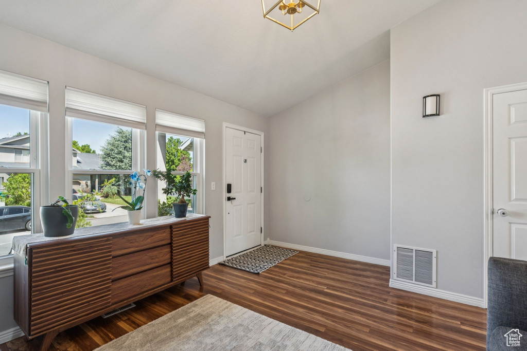 Foyer with dark wood finished floors, a chandelier, and vaulted ceiling
