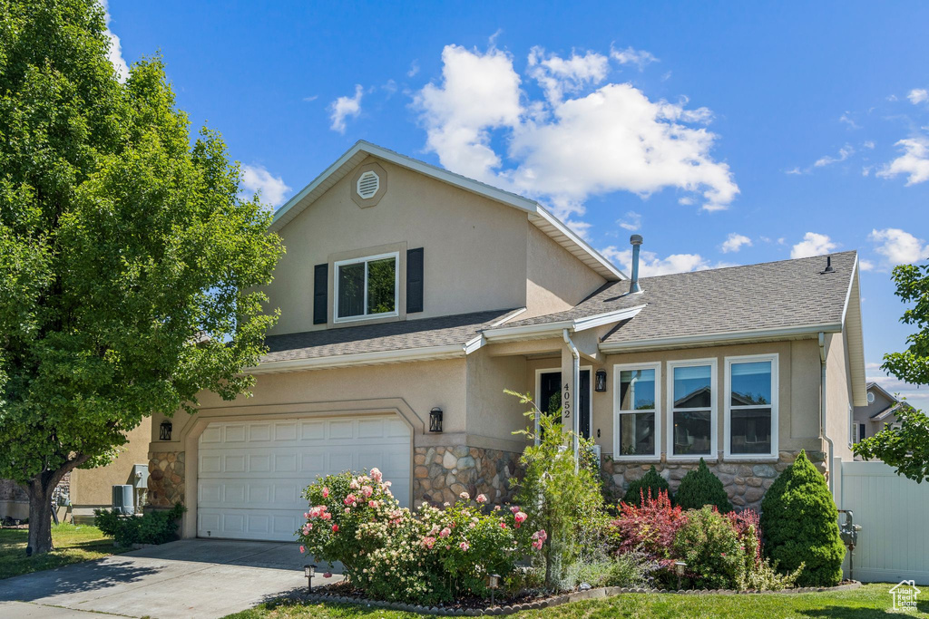 Traditional-style home featuring stone siding, stucco siding, concrete driveway, a garage, and a shingled roof