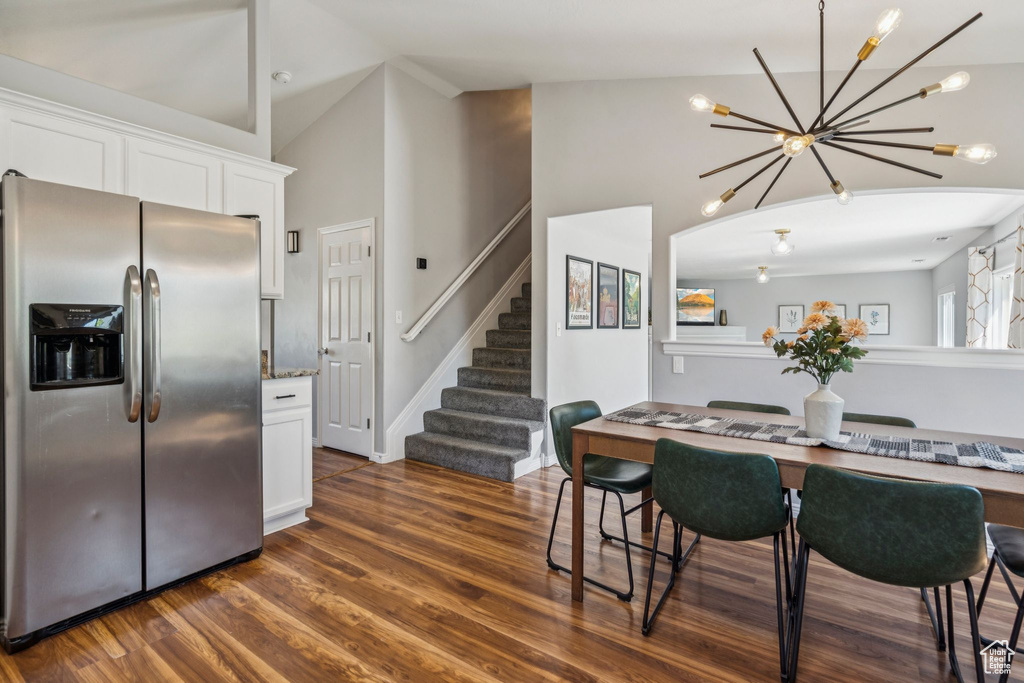 Dining room with a chandelier, stairway, high vaulted ceiling, and dark wood finished floors