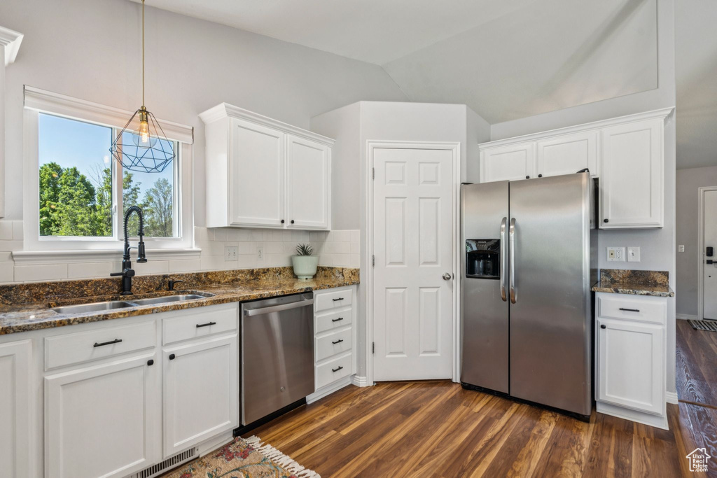 Kitchen featuring stainless steel appliances, dark wood-style floors, white cabinetry, dark stone counters, and lofted ceiling