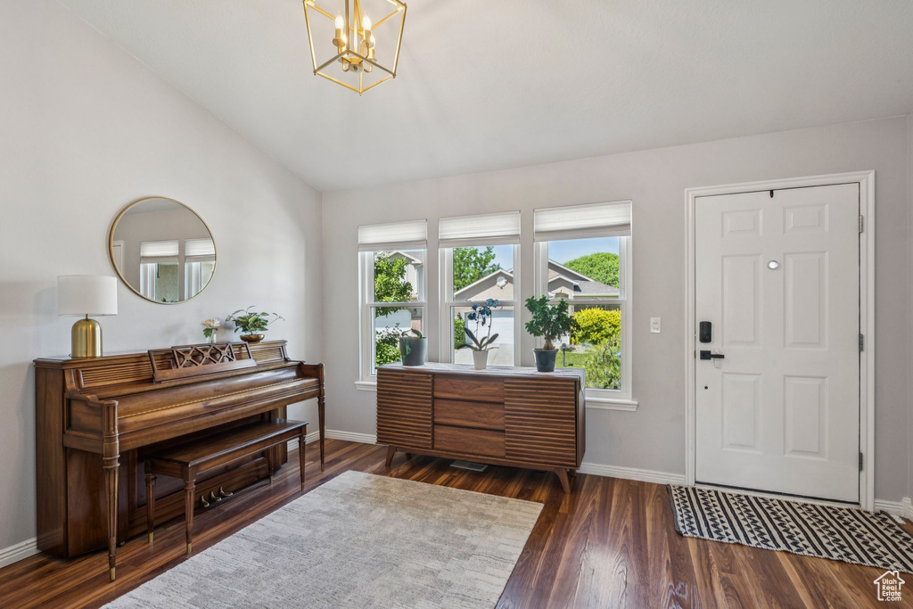 Foyer entrance with a chandelier, lofted ceiling, and wood finished floors