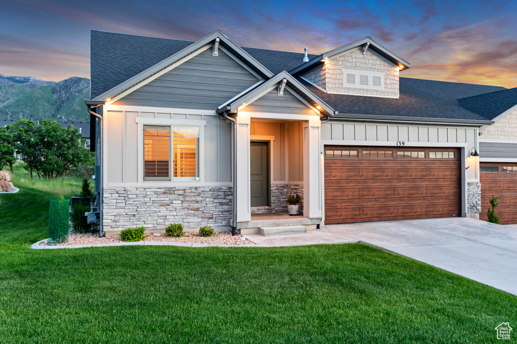 Craftsman-style house featuring roof with shingles, an attached garage, stone siding, and board and batten siding