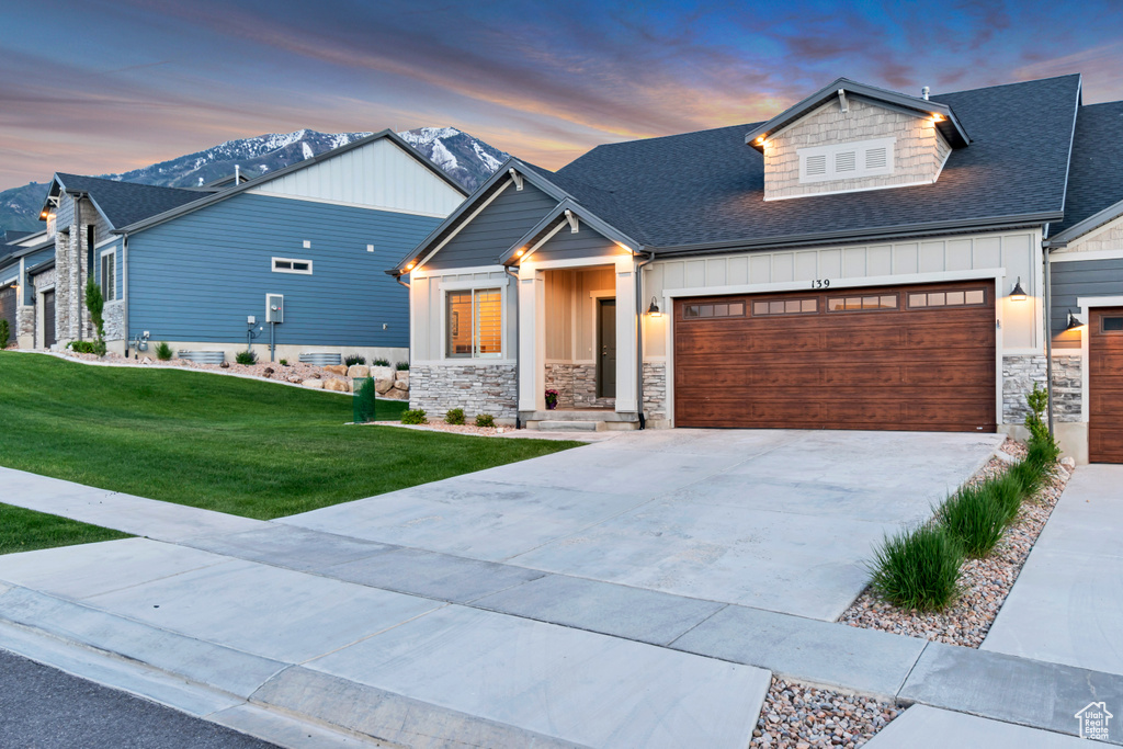 Craftsman inspired home featuring board and batten siding, stone siding, roof with shingles, and a garage