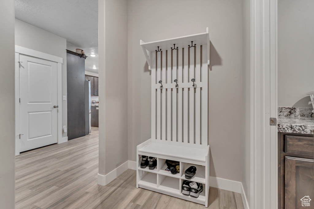 Mudroom featuring light wood-style flooring and baseboards