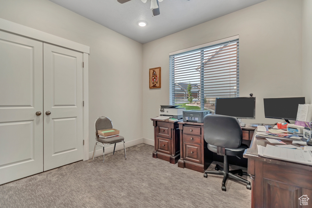 Home office featuring ceiling fan, light carpet, and baseboards