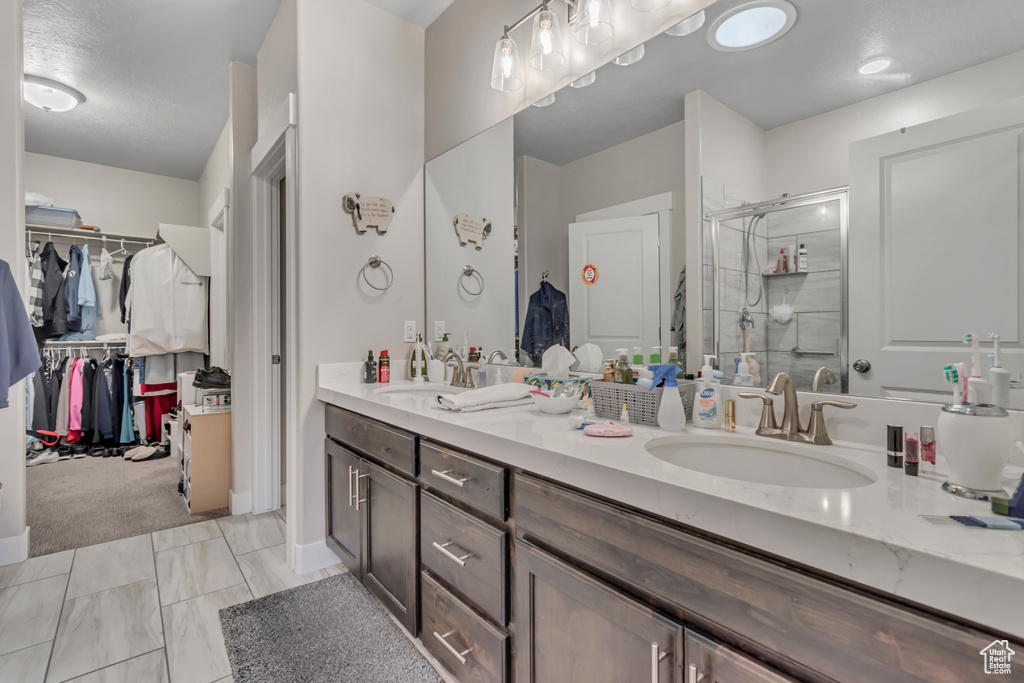Full bath featuring double vanity, a stall shower, and a walk in closet