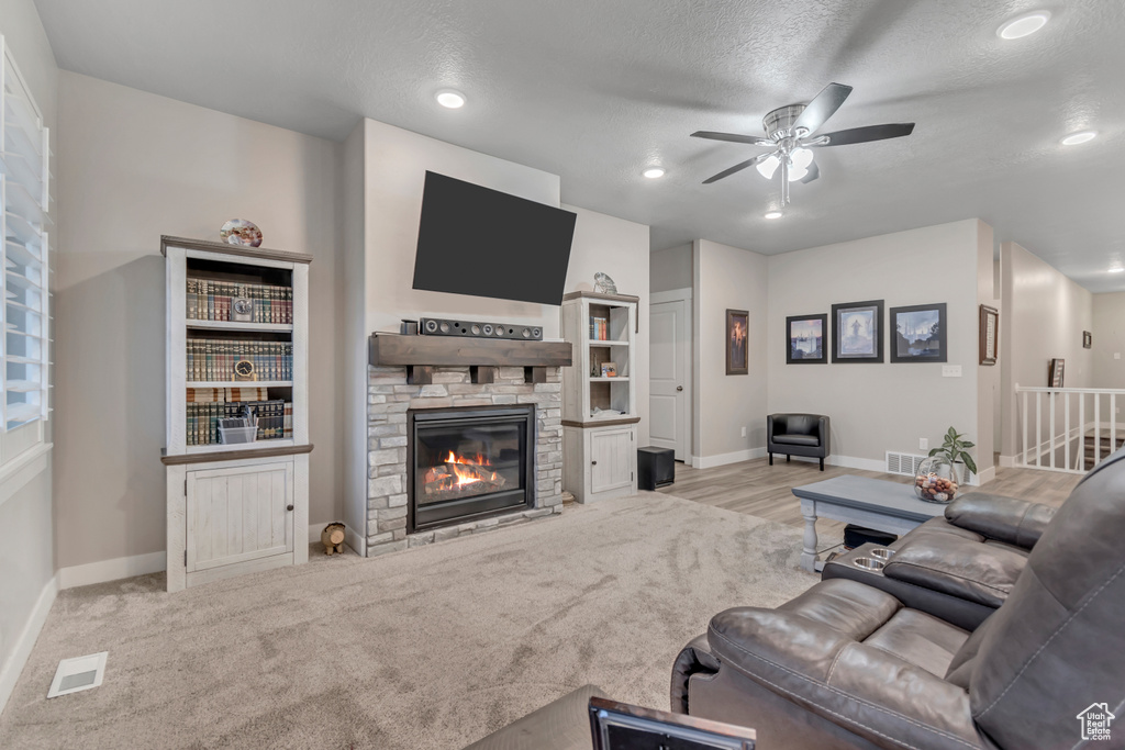 Living area with ceiling fan, a fireplace, baseboards, a textured ceiling, and recessed lighting