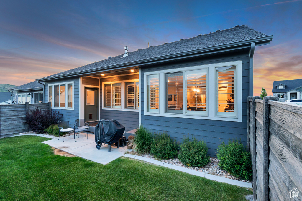Back of property at dusk with a patio area