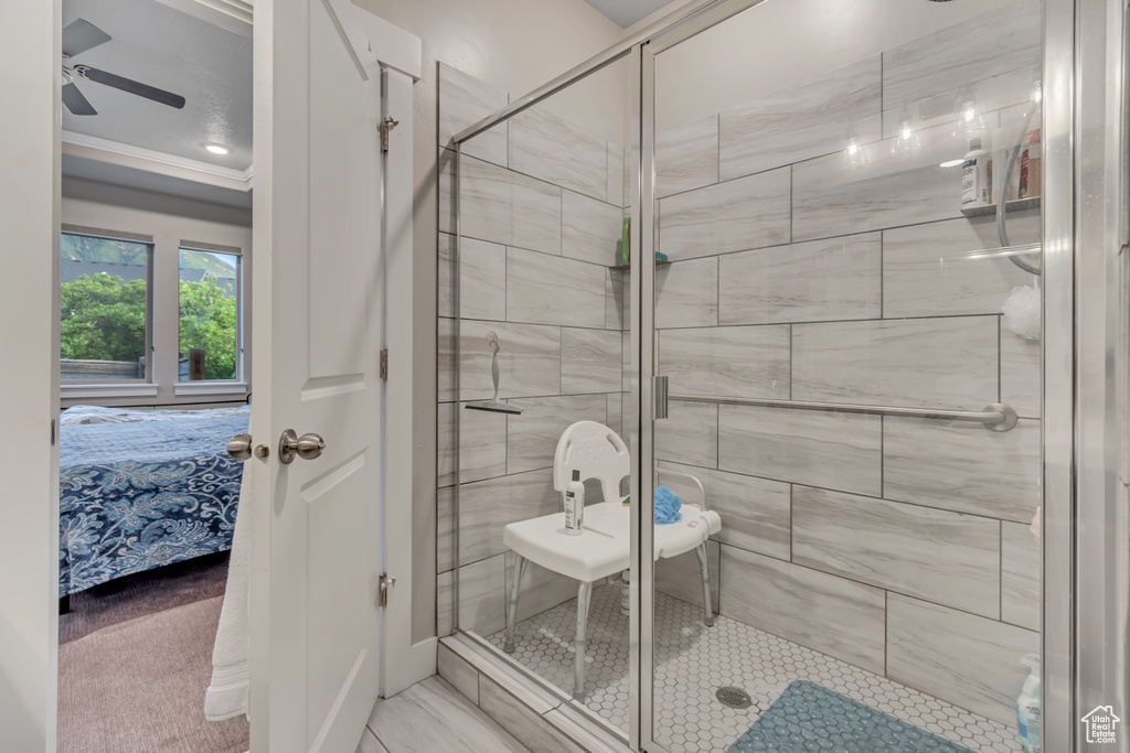 Ensuite bathroom featuring a shower stall, ceiling fan, and ornamental molding