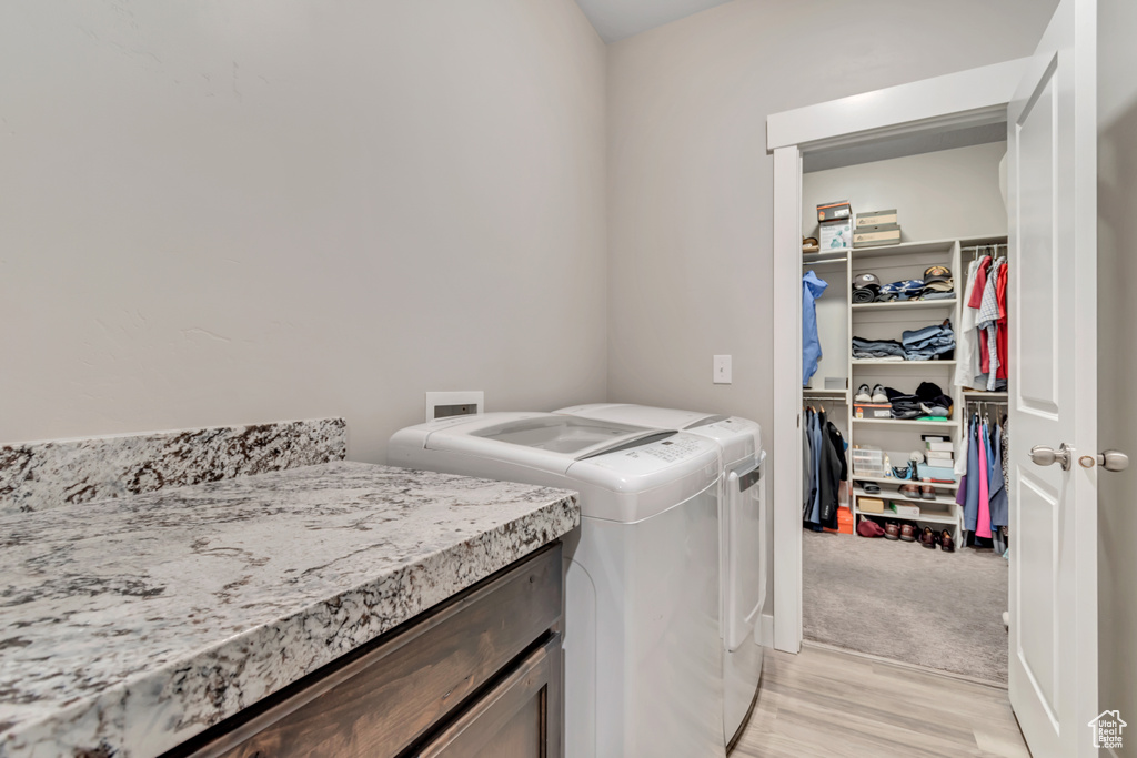 Laundry room featuring washing machine and dryer and light wood finished floors